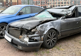 Damaged smashed grey sedan car on the street as a result of a traffic accident is ready for...