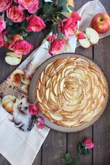 Apple pie. A fragrant apple pie with cinnamon, set against a background of roses and red apples. A delicious treat for the autumn season. Homemade pastries. Food. Sweet apples. Pie 