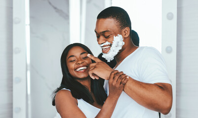 Portrait Of Cheerful African American Couple Having Fun In Bathroom, Happy Young Black Spouses Fooling Together While Getting Ready In The Morning, Embracing And Laughing At Home, Copy Space