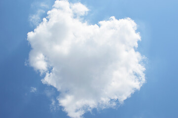 A beautiful white heart-shaped cloud, backlit by the sun. Beauty in nature. Sun rays.