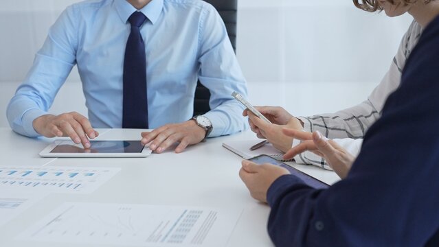 Business team working together, analyzing financial charts and data on digital tablet and smartphones, during a productive meeting in a modern office