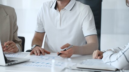 Professional team analyzing financial charts, working together in sleek workspace, strategizing company performance with collaborative energy and shared insights, close up