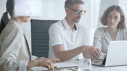 Business team collaborating and analyzing data on a laptop during a productive office meeting, discussing strategies and making informed decisions