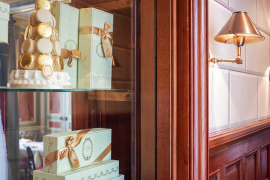 Paris, France - April 16, 2018: Elegant Laduree display of macarons and gift boxes in a stylish wooden cabinet, showcasing exquisite pastry presentation and luxurious ambiance