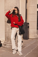 Autumn or spring trendy outfit woman in stylish red sweater, black bag, beige pants jeans,...