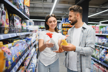 Couple choosing cleaning products in supermarket aisle