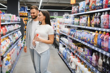 Couple shopping household chemicals choosing cleaning supplies aisle