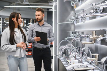 Sales assistant helping customer choosing new plumbing faucets
