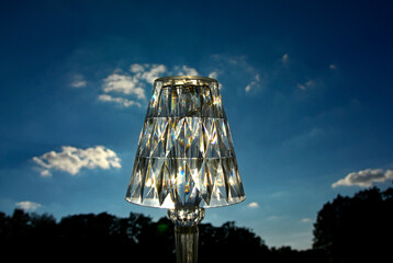 lampka z pleksi na tle nieba, dekoracyjna lampka stołowa oświetlona słońcem na tle nieba, decorative table lamp illuminated by the sun against the sky,