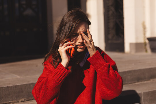 Sad woman listen bad news on mobile phone complaining alone in the stairs. Upset young woman thinking about her problems. Girl have mobile phone call conversation. Negative, bad news, breakup, unhappy - Powered by Adobe
