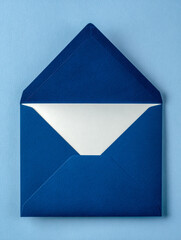 Open blue envelope with white inner lining laying flat on a light blue background symbolizing communication or invitations in an elegant and minimalistic style