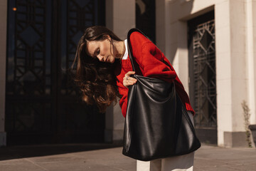 Elegant young long brunette hair woman looking in her black leather bag her phone or purse....