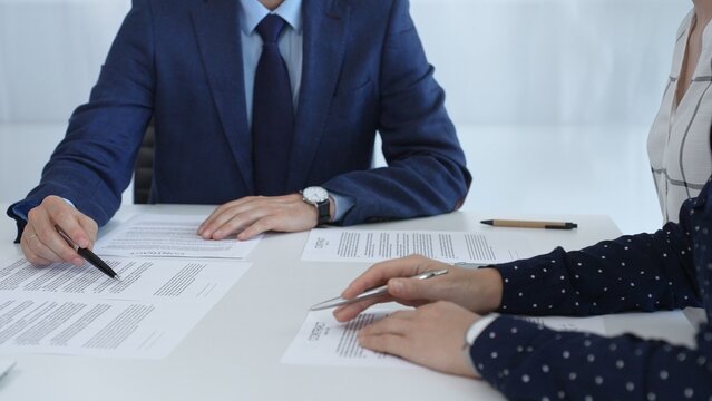 Business people reviewing contract during a meeting, pointing at specific clauses and discussing potential amendments before signing the agreement - Powered by Adobe
