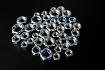 Scatter of Chrome Hex Nuts with Blue Nylon Locking Inserts on a Dark Surface, Metal Fasteners of Various Sizes, Engineering Hardware and Industrial Equipment
