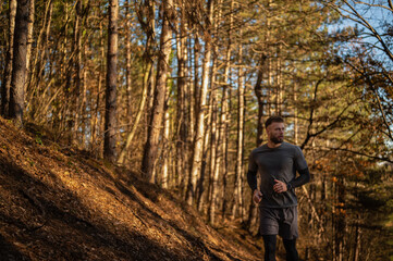 Male athlete running uphill in forest during golden hour
