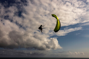 Extreme paragliding pilot soaring in the New Zealand beach. Adventure concept