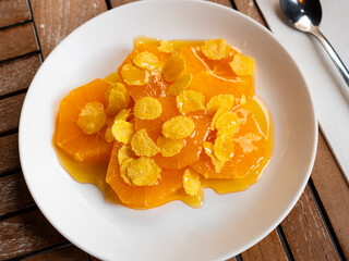 Healthy breakfast, lunch or snack on white plate. Orange slices with honey and sprinkled with corn flakes