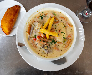 Hearty Latin American peanut soup, sopa de mani, with short tube noodles and meat with empanada. In Bolivian tradition, served with crispy fried potatoes and greens