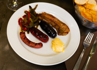 Grilled sausages and meat served with stewed vegetables and red wine