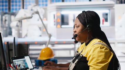 African American engineer offers service from solar panel call center, managing help line requests for support and maintenance. Customer support operator improve factory operations. Camera A.