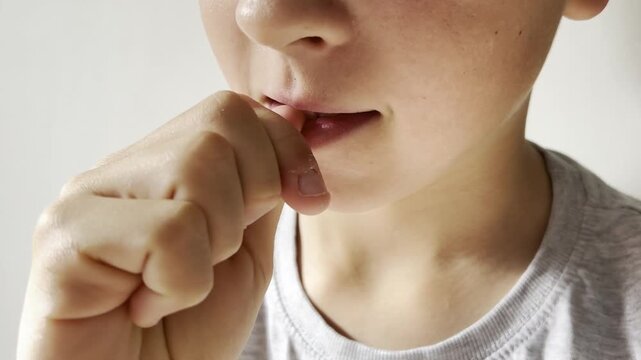 Child biting nails close up, showing stress habit and anxiety concept