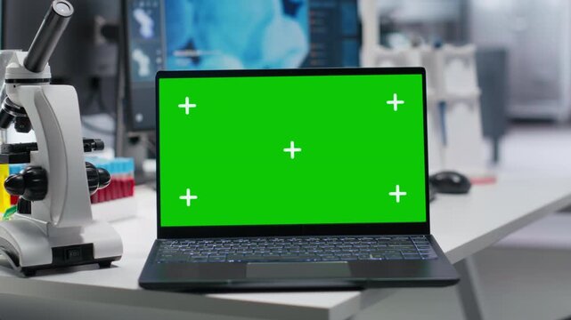 Green screen laptop in empty laboratory workspace with testing tools, scientific instruments capture the environment of bioscience research and medical discovery. Molecular biology and diagnostics.