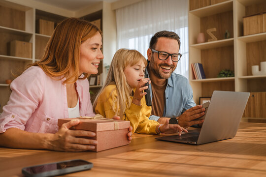 Family celebrating birthday on video call with gift box