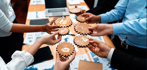 A diverse team engages in a collaborative brainstorming session, using symbolic gear pieces to represent various financial and strategic concepts in a modern office environment. Amity