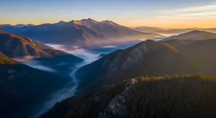 Fototapeta premium Majestic mountain range bathed in the warm glow of sunrise, with mist swirling through the valleys below