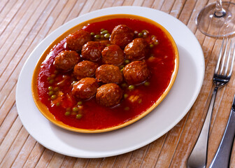 Tasty meatballs with garden-style vegetables, stewed in tomato sauce with spices served for dinner. Spanish cuisine..
