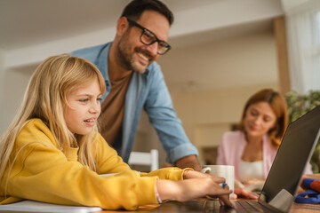 Family helping child with online learning on laptop