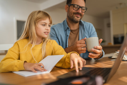 Father and daughter learning online with laptop