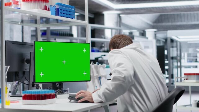 Green screen at biolab desk used by man researcher with laboratory tech, focusing on genetics research, nanotechnology and healthcare data for medical discovery and innovation. Camera B.