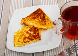 Appetizing folded thin crepes filled with chocolate spread and sliced bananas served with aromatic herbal tea for breakfast..