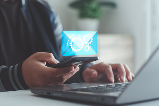 Person using smartphone with email automation icon, featuring gears and message envelope, representing automated email marketing, business communication, digital tools and efficiency.