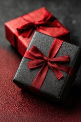 Elegant black gift boxes with red ribbons on a textured surface