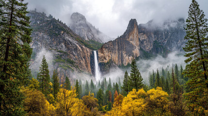 Majestic waterfall cascading down rugged mountain cliffs surrounded by vibrant autumn trees and mist in a dense forest landscape on a cloudy day