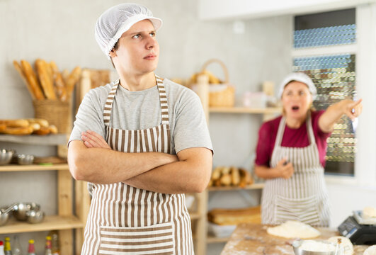 During working day, quarrel broke out between boss and employee. Embarrassed male cook-baker stands in kitchen of bakery, quarrels with female boss, listens to accusations and insults.