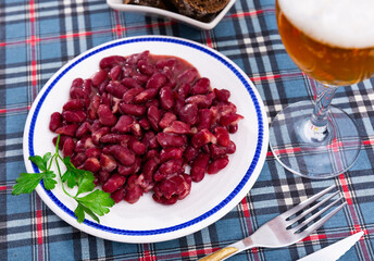 Restaurant serves light and low-calorie lunch - stewed boiled vegetables, boiled kidney beans with glass of bear, slices of rye bread.