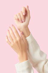 Beautiful groomed womans hands with pink matte nail design on a pink background