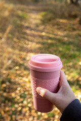 Woman holding cup of coffee in autumn park