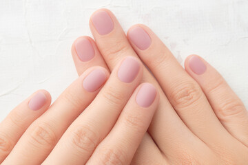 Womans hands with trendy pink matte manicure close-up. Beauty salon. 