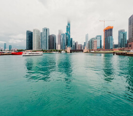 Majestic views of iconic Chicago, Illinois urban architecture and Lake Shore Drive as viewed from the Chicago River and Lake Michigan. A tour boat glides on the water.