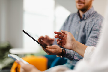 Business meeting in a modern office space with professionals discussing strategies using tablets during daytime
