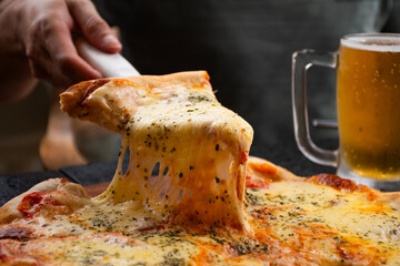 man's hand serving delicious slice of mozzarella pizza with spatula and melted cheese falling from the slice