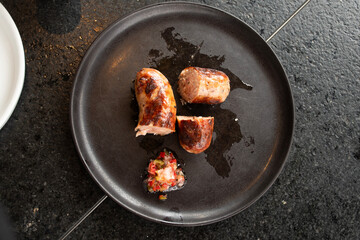 sliced ​​chorizo ​​pork sausage on black plate top view with vinaigrette