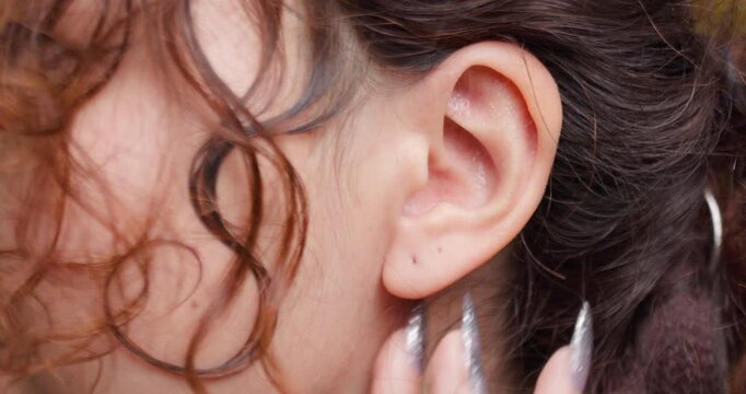 Close-up view of a Kazakh woman's ear with detailed texture and curly hair