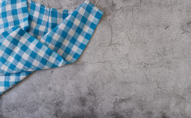 A blue and white checkered napkin is placed on a gray surface. Restaurant or kitchen concept.
