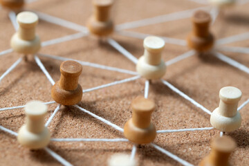 Wooden pushpins connected by white string on a corkboard, illustrating a social network, people...