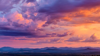 Obraz premium Colorful sunset sky with billowing clouds over mountain landscape, vibrant orange, purple, and pink hues create dramatic, peaceful atmosphere